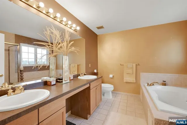 a spacious bathroom with a double vanity sink a mirror and a bathtub