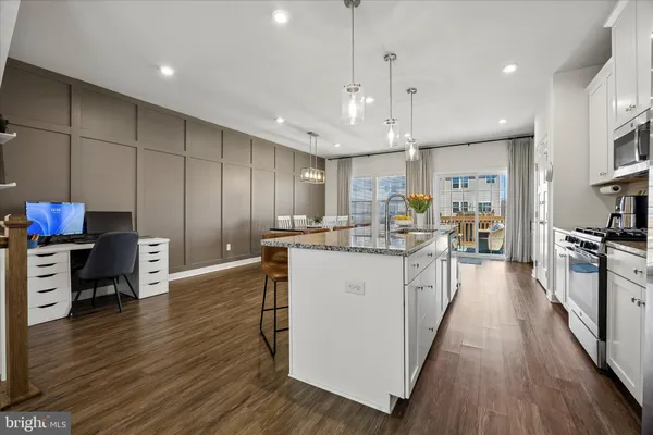 a kitchen with stainless steel appliances granite countertop a refrigerator a stove top oven a sink dishwasher and a dining table with wooden floor