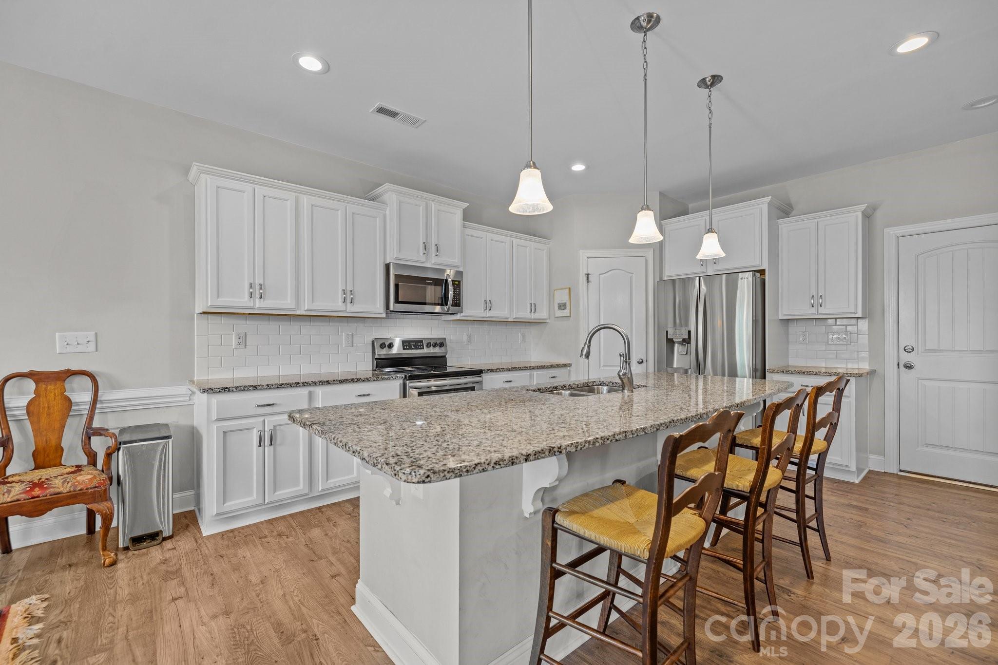 4697 Rinaldo Road York, SC 29745 - Photo 9 of 37 a kitchen with stainless steel appliances granite countertop a stove top oven a sink a dining table and chairs with wooden floor