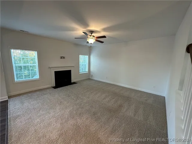 an empty room with windows and ceiling fan