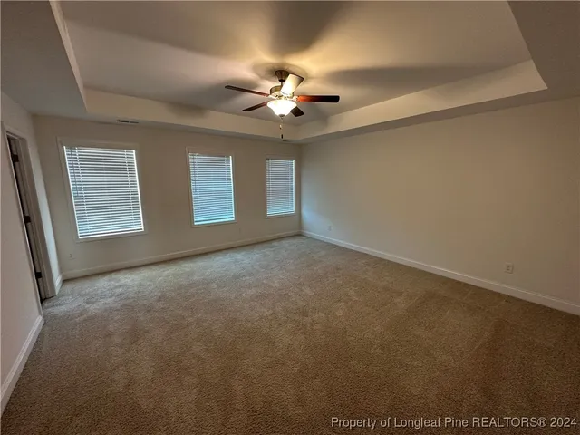 an empty room with windows and ceiling fan