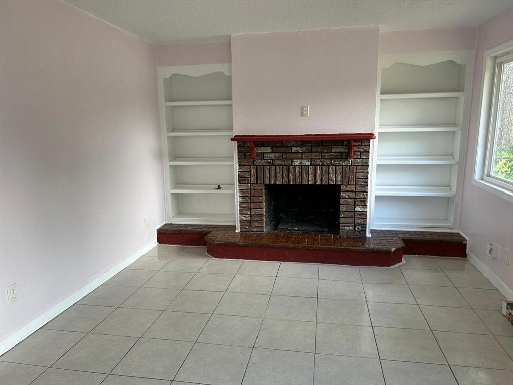 10034 Mill Valley Lane Dallas, TX 75217 - Photo 4 of 18 a room with a fireplace and a book shelf
