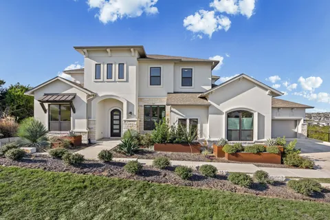 a front view of a house with lots of garden and plants