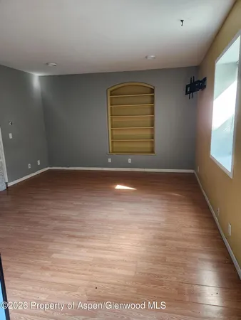 an empty room with wooden floor and windows