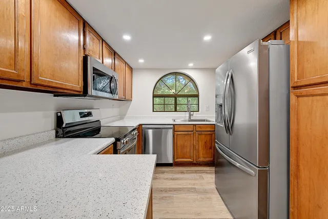 a kitchen with stainless steel appliances granite countertop a refrigerator a stove top oven a sink and dishwasher
