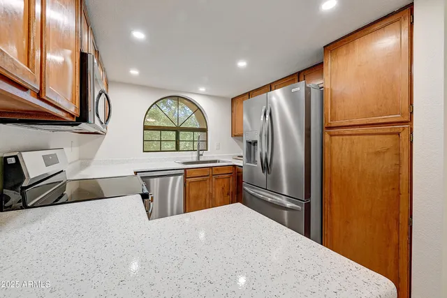 a kitchen with stainless steel appliances granite countertop a refrigerator a stove and a sink