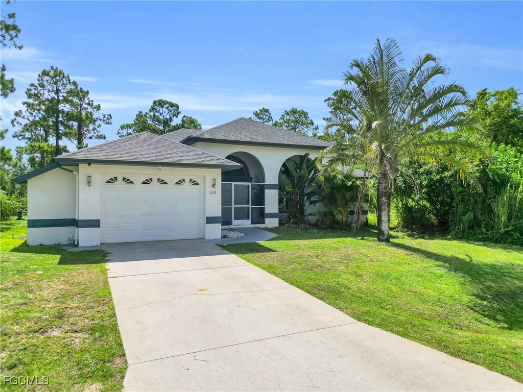 809 Hamilton Avenue Lehigh Acres, FL 33972 - Photo 2 of 25 a front view of a house with garden