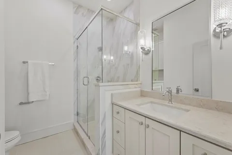 a bathroom with a granite countertop sink a mirror and a shower