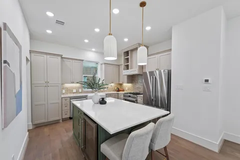 a kitchen with stainless steel appliances a dining table chairs stove refrigerator and cabinets