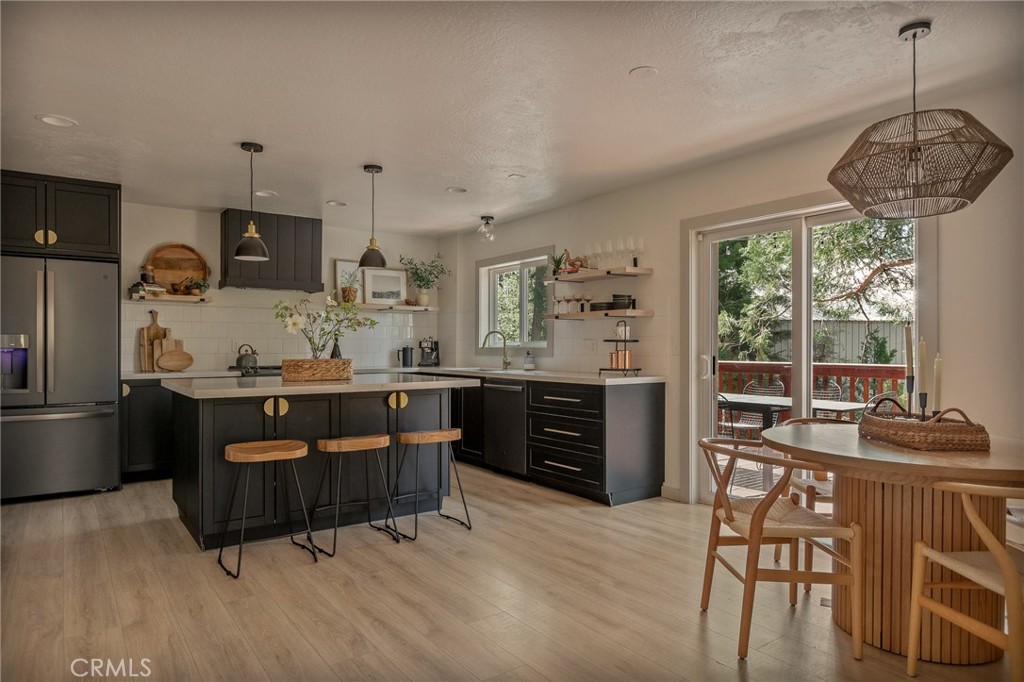 373 Summit Road Lake Arrowhead, CA 92352 - Photo 4 of 41 a kitchen with stainless steel appliances kitchen island granite countertop a refrigerator a stove a sink a dining table and chairs with wooden floor