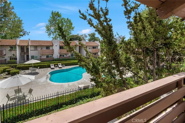 a view of a swimming pool with lawn chairs under an umbrella