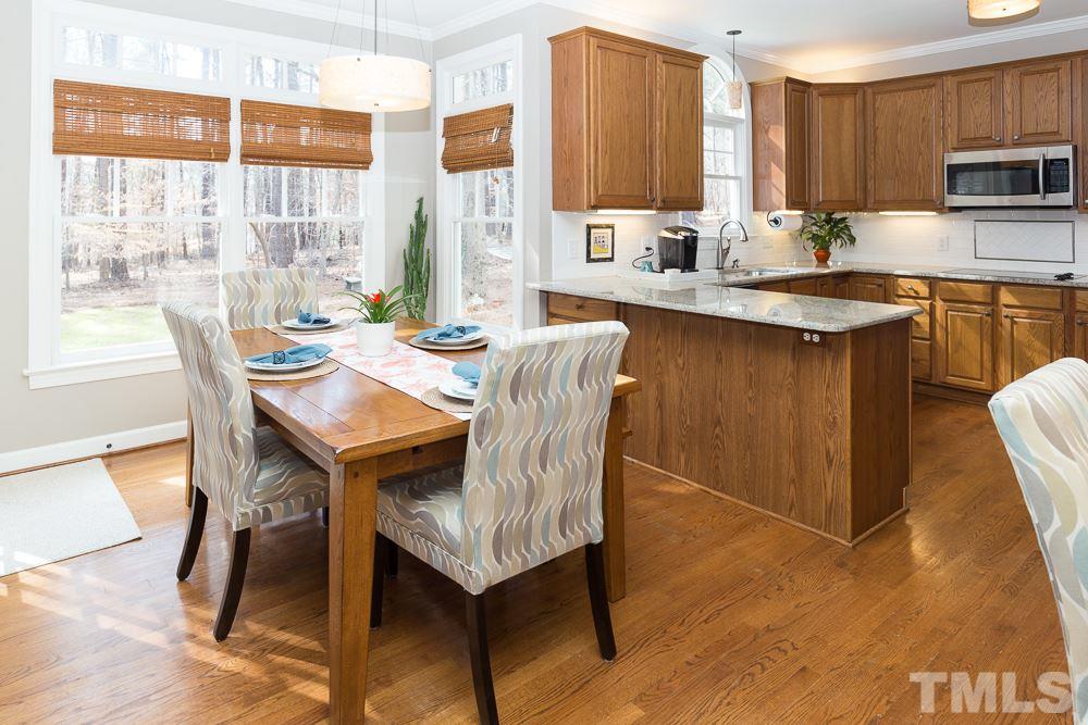 5817 North Hawthorne Way Raleigh, NC 27613 - Photo 7 of 25 a dining room with furniture a large window and a wooden floor