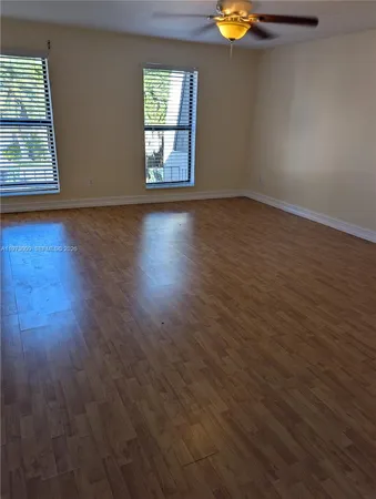 an empty room with windows and wooden floor