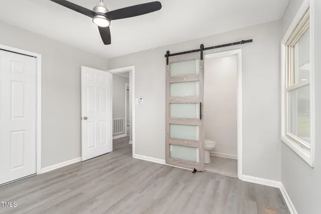 an empty room with wooden floor closet and windows