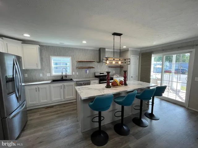 a kitchen with stainless steel appliances a dining table chairs refrigerator and microwave
