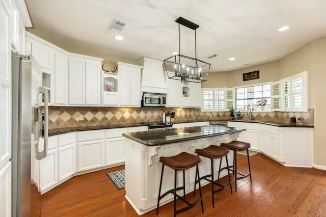 a kitchen with stainless steel appliances granite countertop a stove and white cabinets
