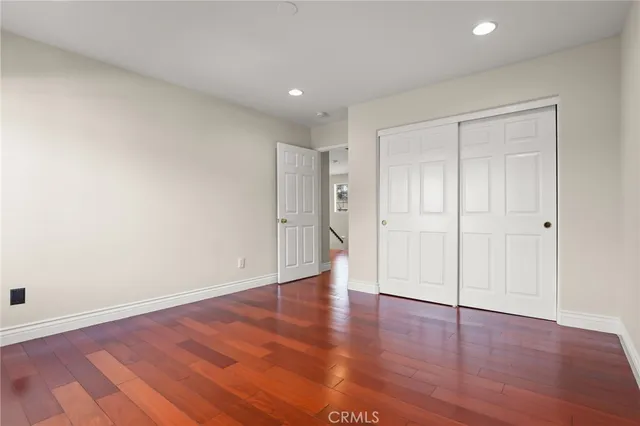 an empty room with wooden floor and ceiling fan