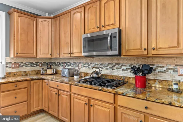a kitchen with stainless steel appliances granite countertop white cabinets and a stove top oven
