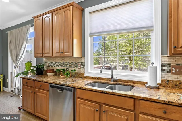 a kitchen with stainless steel appliances granite countertop a sink a counter space and a window