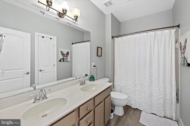a bathroom with a granite countertop sink toilet a large mirror a shower and a window