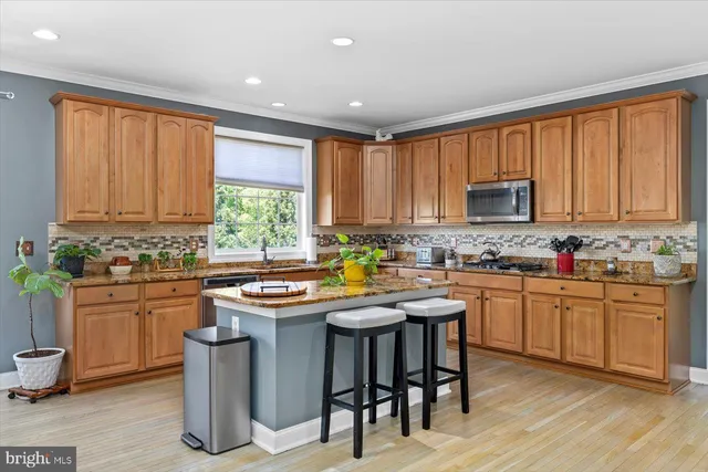 a kitchen with stainless steel appliances granite countertop wooden cabinets a stove top oven a sink and dishwasher with wooden floor