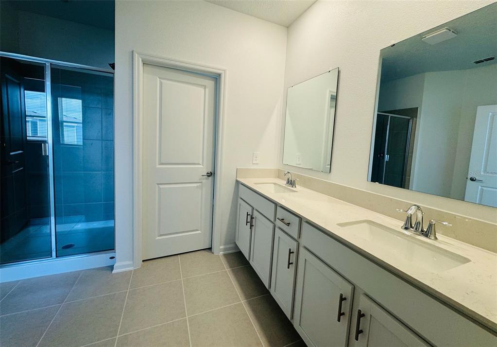 2473 Spring Tune Alley Kissimmee, FL 34744 - Photo 20 of 27 a spacious bathroom with a double vanity sink a mirror and a shower