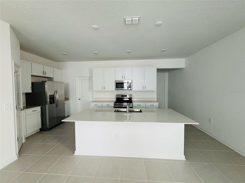 2473 Spring Tune Alley Kissimmee, FL 34744 - Photo 8 of 27 a large kitchen with stainless steel appliances a large counter top a stove and a refrigerator