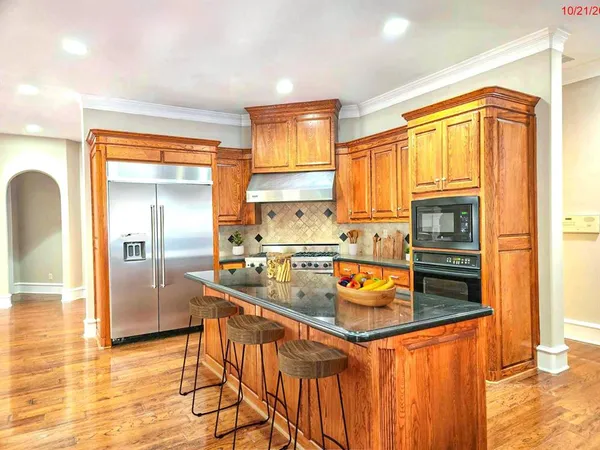 a kitchen with stainless steel appliances granite countertop a refrigerator a stove and a sink with wooden floor