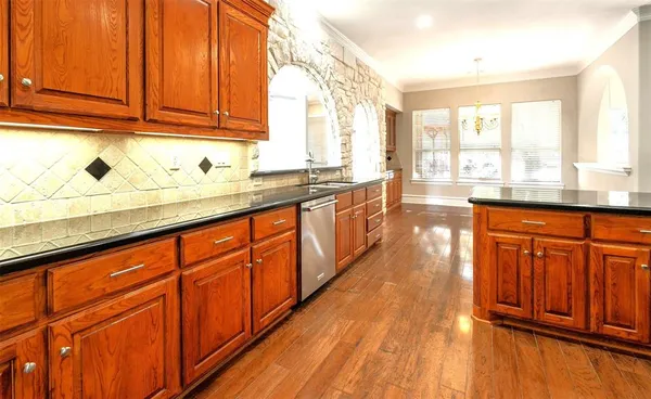 a kitchen with stainless steel appliances granite countertop wooden cabinets a sink and dishwasher with wooden floor