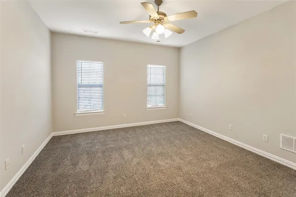 an empty room with windows and fan