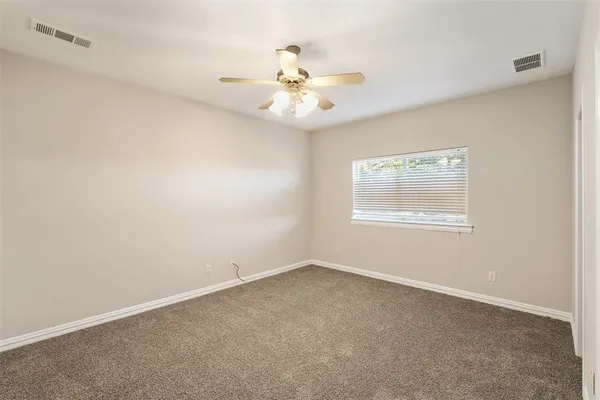 an empty room with a window and a fan