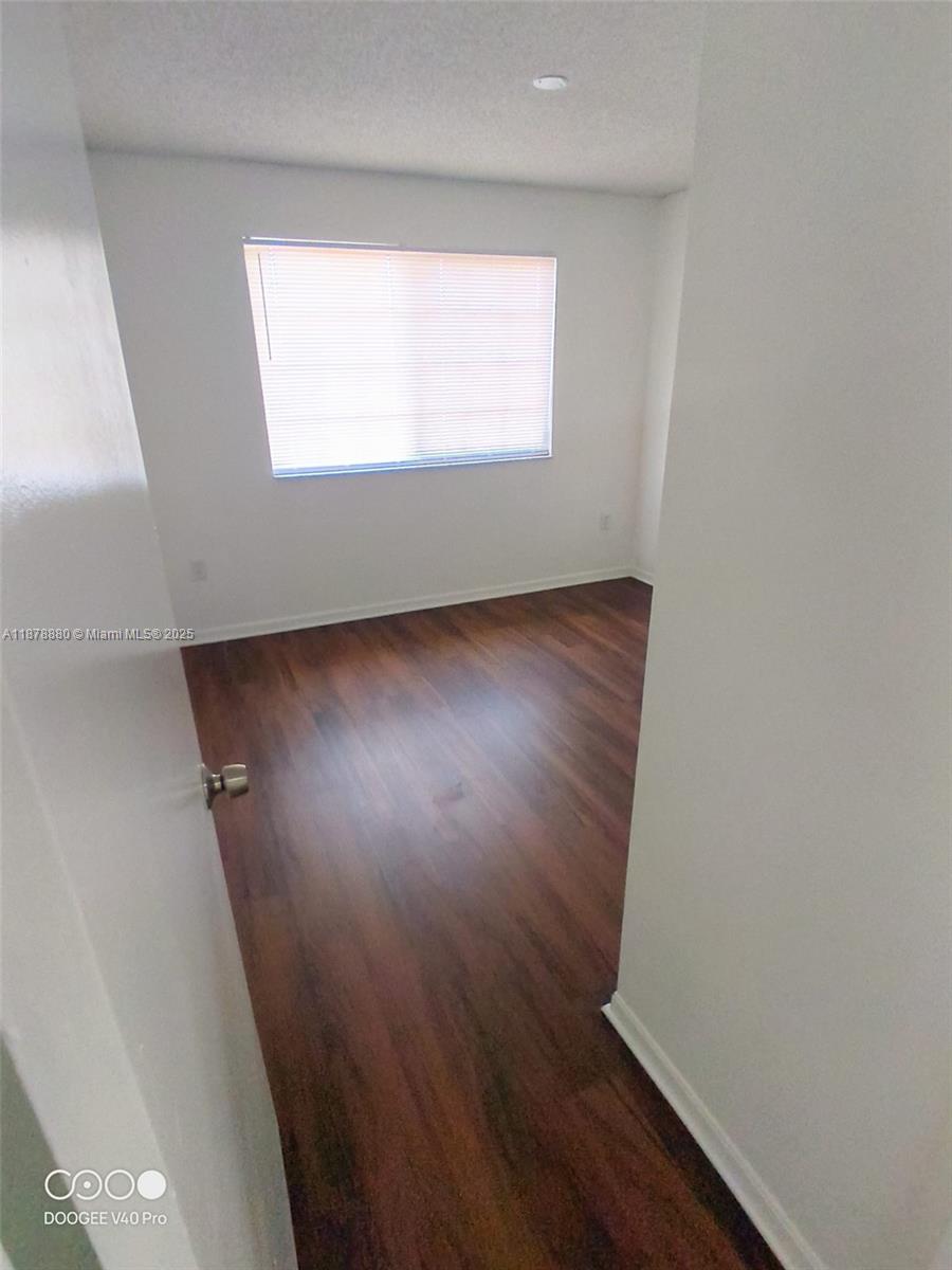 4183 Haverhill Road, Unit 712 West Palm Beach, FL 33417 - Photo 5 of 11 an empty room with wooden floor and windows