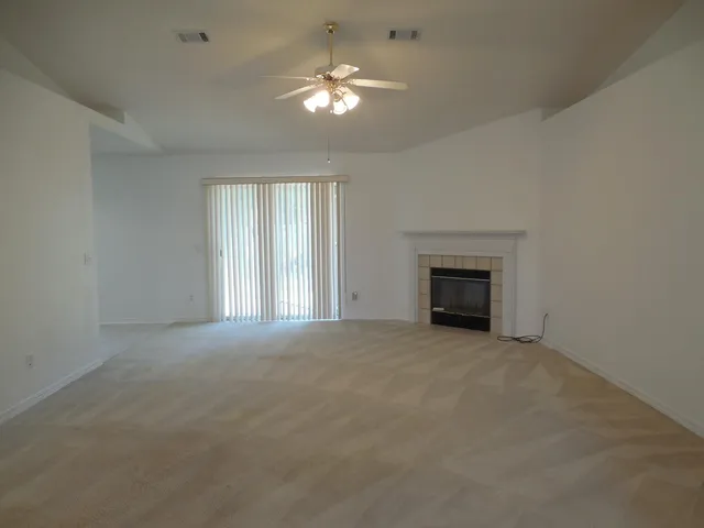 an empty room with chandelier fan and windows
