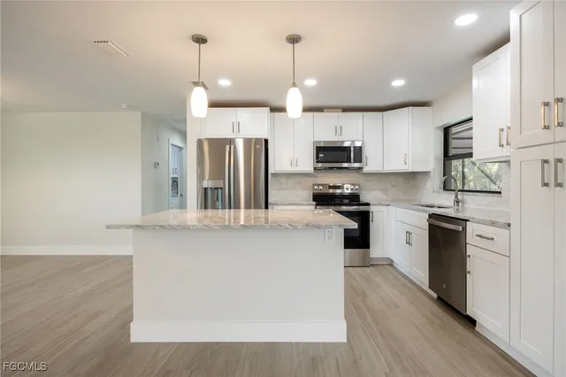 a kitchen with kitchen island a refrigerator a stove a sink and white cabinets