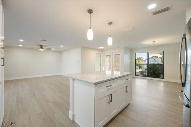 a view of a kitchen island a chandelier and wooden floor