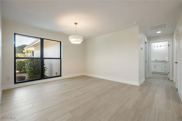 an empty room with wooden floor mirror and windows