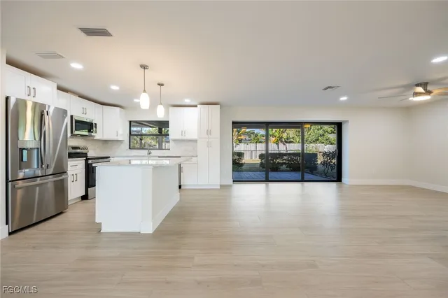a large white kitchen with a refrigerator a stove a sink and a cabinets
