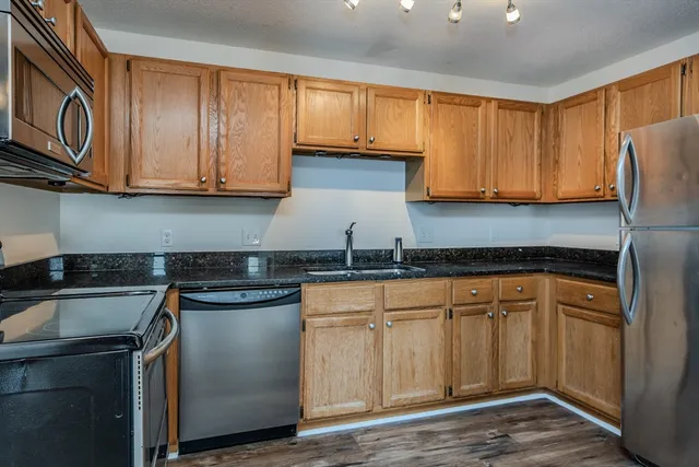 a kitchen with stainless steel appliances granite countertop a stove a sink and a microwave