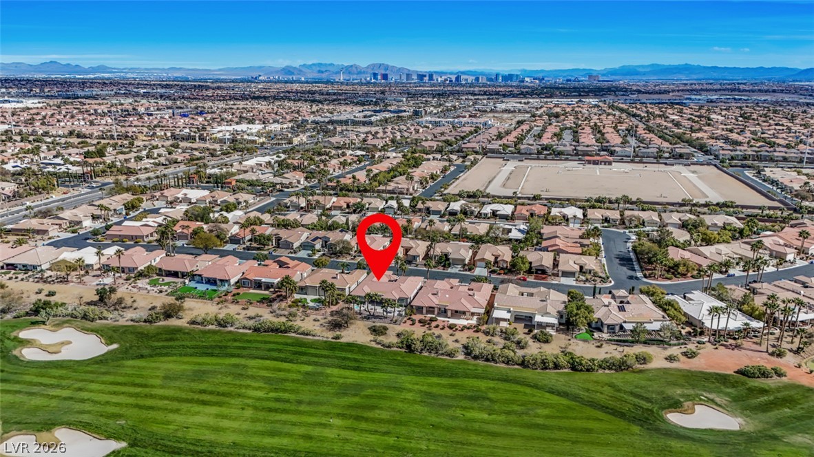 5015 Rivedro Street Las Vegas, NV 89135 - Photo 84 of 91 An aerial perspective showcases a residential neighborhood nestled beside a verdant golf course, offering distant cityscape and mountain vistas.