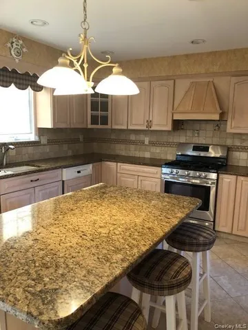 a kitchen with kitchen island granite countertop a sink a stove and cabinets