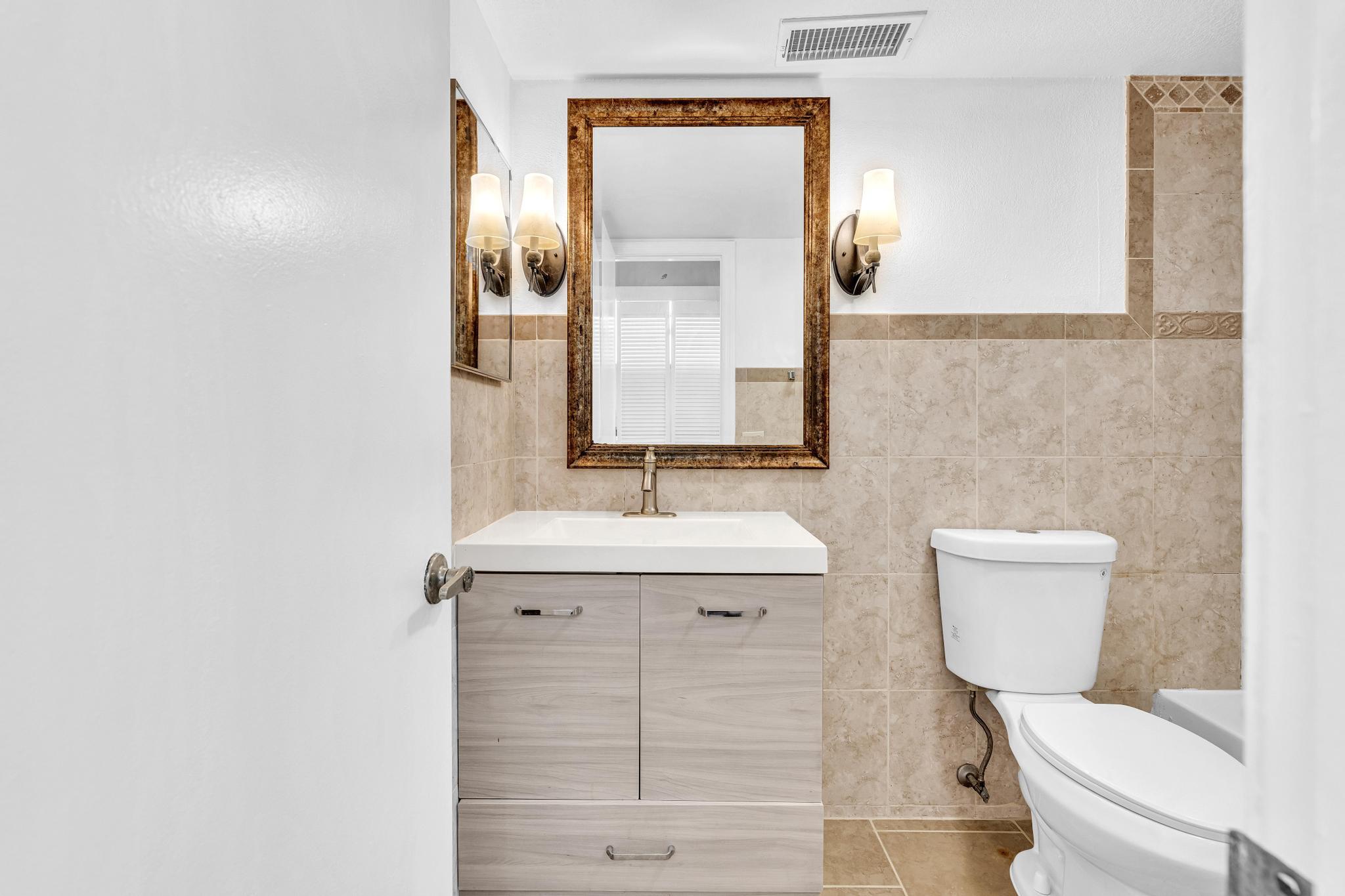 1291 Northwest 13th Street, Unit 445D Boca Raton, FL 33486 - Photo 35 of 50 a bathroom with a sink a toilet and mirror