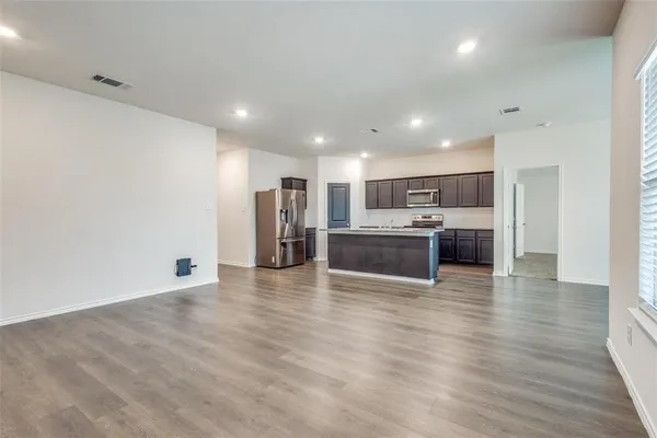 a view of kitchen with kitchen island wooden floor center island and stainless steel appliances