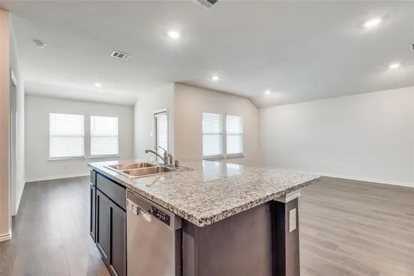 a kitchen with granite countertop kitchen island a sink appliances and wooden floor