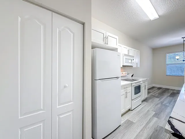 a kitchen with a refrigerator a stove and white cabinets