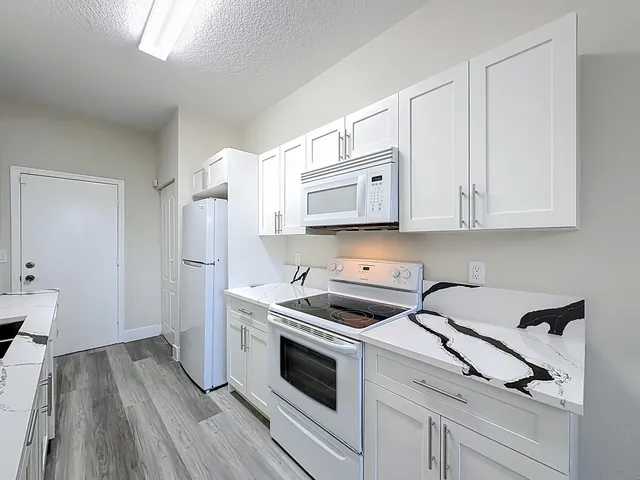 a kitchen with white cabinets and white appliances