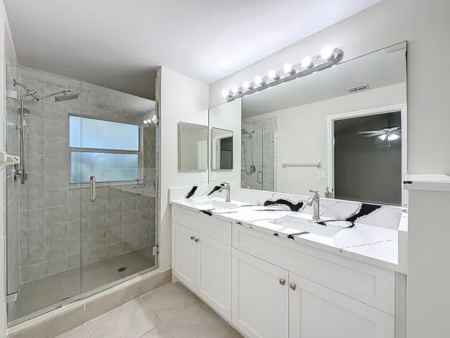 a bathroom with a double vanity sink mirror and shower