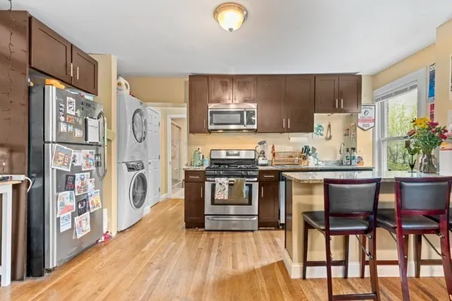 a kitchen with stainless steel appliances granite countertop a stove top oven a dining table and chairs with wooden floor