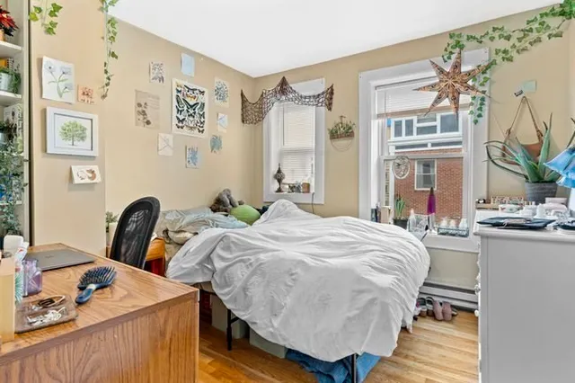 a bed sitting in a bedroom next to a window with wooden floor