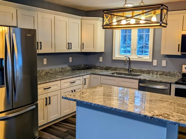 a kitchen with stainless steel appliances granite countertop a sink stove microwave and refrigerator