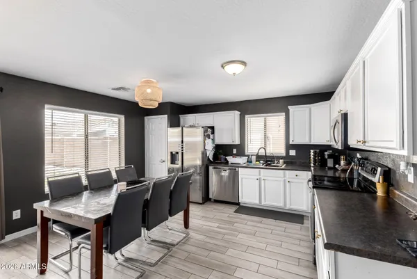 a kitchen with stainless steel appliances granite countertop a sink dishwasher stove refrigerator dining table and chairs